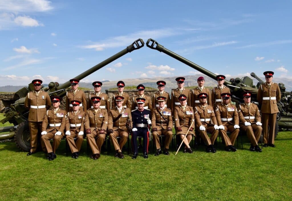 Soldiers pose in front of artillery.