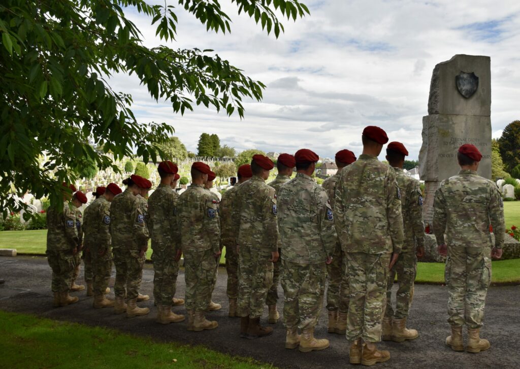 Group of cadets standing in two rows in front of memorial