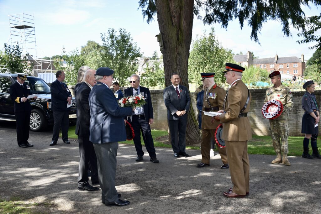 Local dignitaries standing in circle with some holding wreaths
