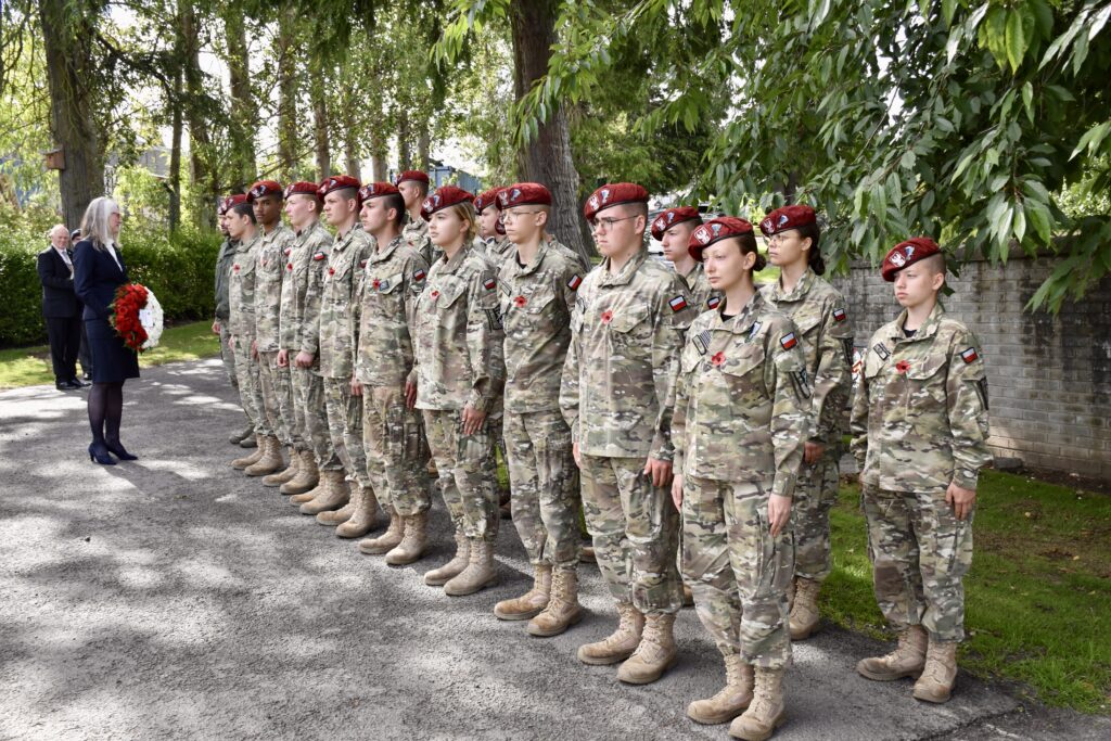 Polish Cadets standing in two rows with woman holding wreath