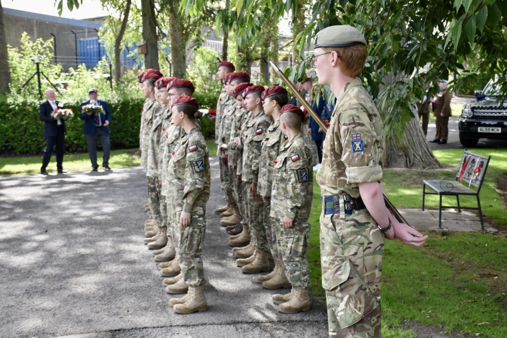 Cadets standing two rows with local dignitaries in the background