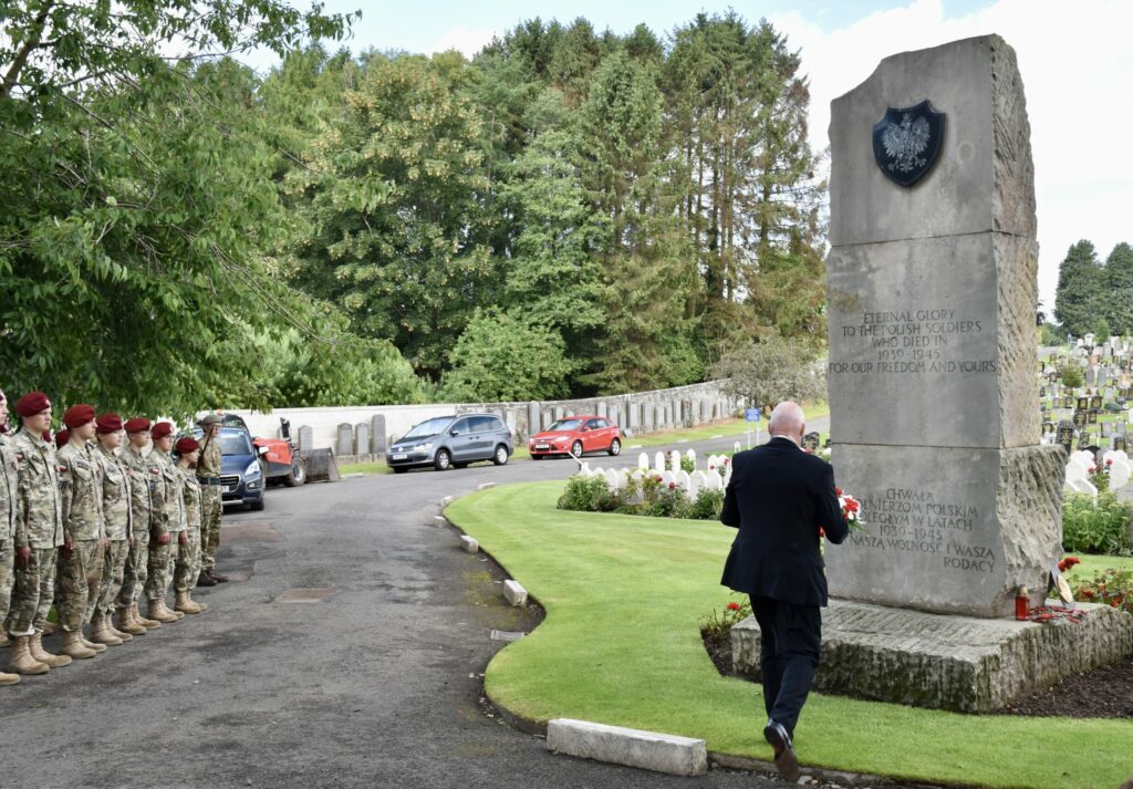 Group of cadets standing while local dignitary lays wreath at memorial