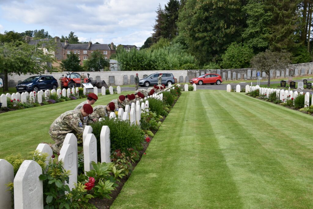 Seventeen Polish cadets crouched in front of war graves