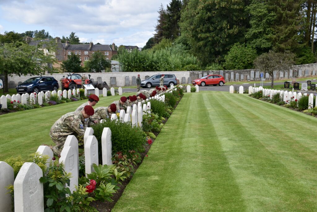 Seventeen Polish cadets crouched in front of war graves