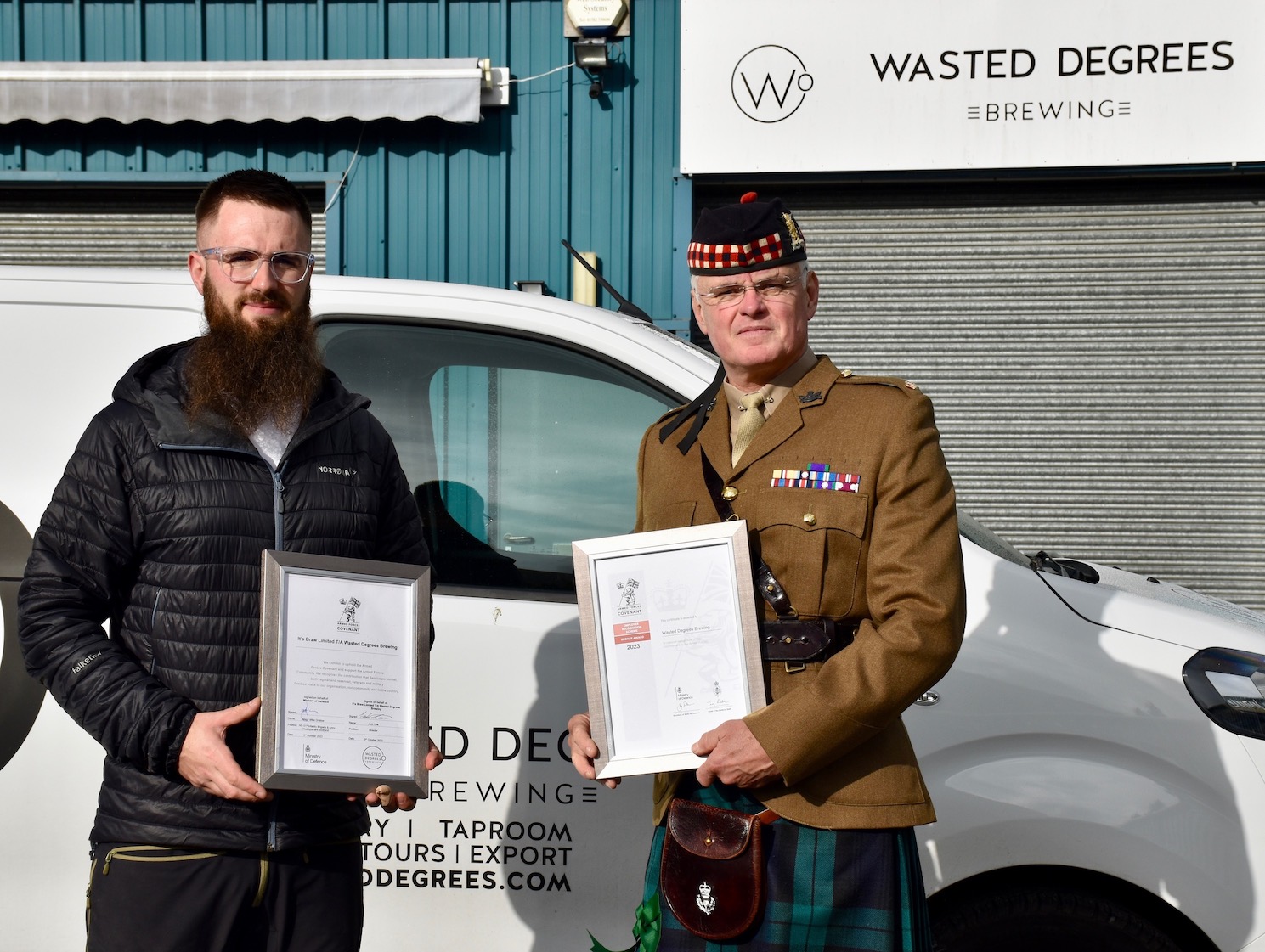Wasted Degrees co-owner and 51 Infantry Brigade's Engagement Coordinator holding the Armed Forces Covenant and Employer Recognition Scheme Bronze Award certificates