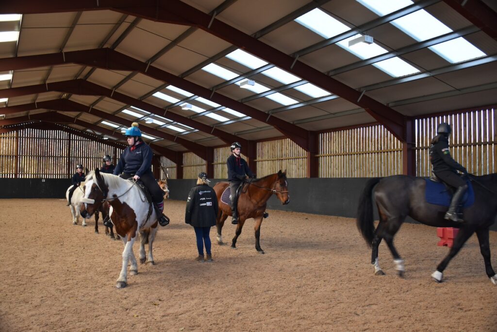 Six people riding horses with Emma instructing