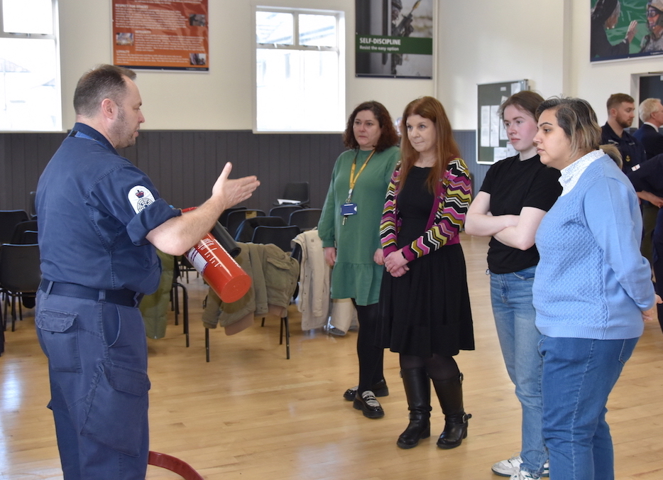 Explaining how to use a fire extinguisher.