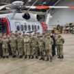 A group of cadets standing beside an HM Coastguard helicopter.