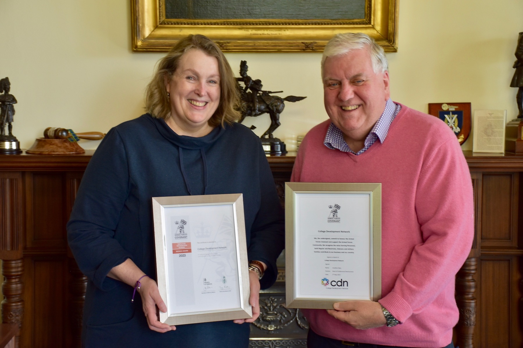 Two people displaying the Armed Forces Covenant and ERS Bronze Award certificates.