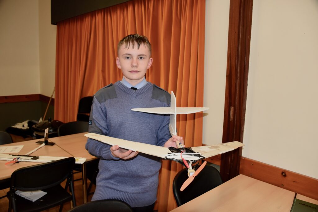 Cadet holding a wooden model glider.