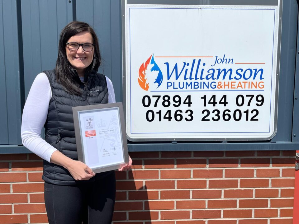 Woman holding a certificate outside an office building.