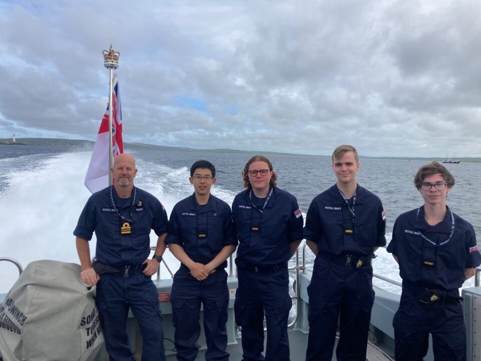 Five members of URNU East Scotland at the stern of a vessel.