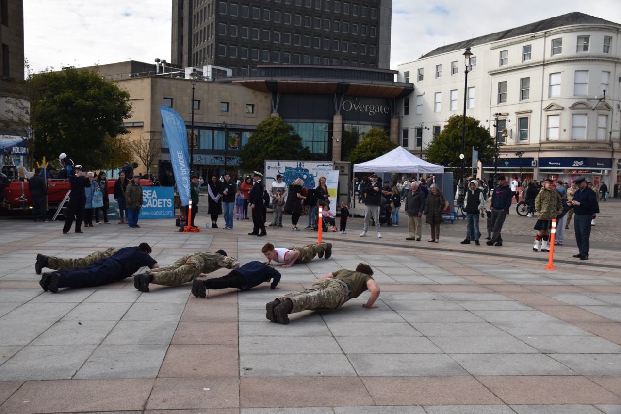 Cadets and Physical Training Instructor doing press-ups in front of a crowd.