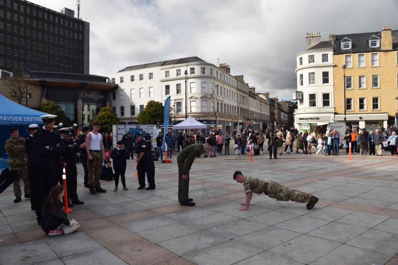A cadet doing press-ups in front of another cadet and a crowd.