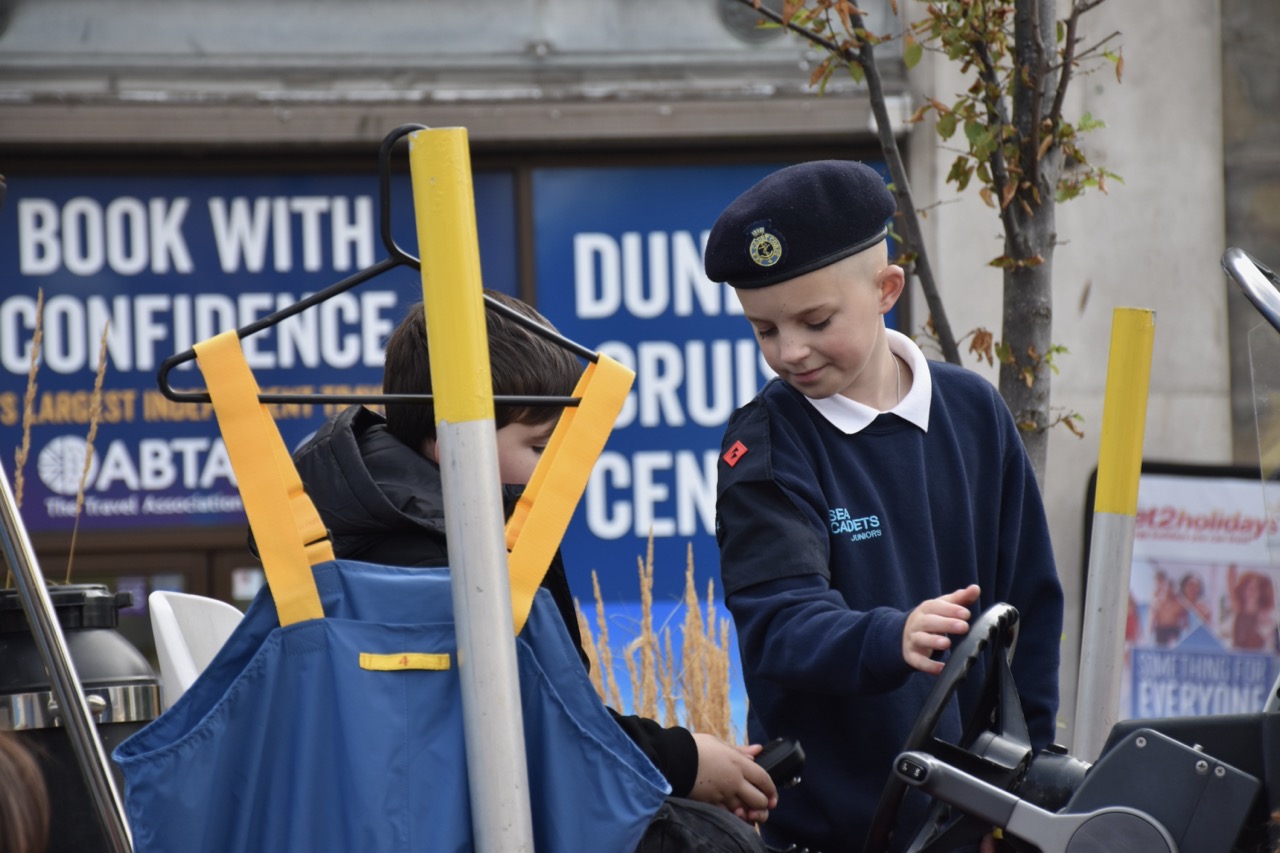 A cadet showing a child how to steer the dinghy.