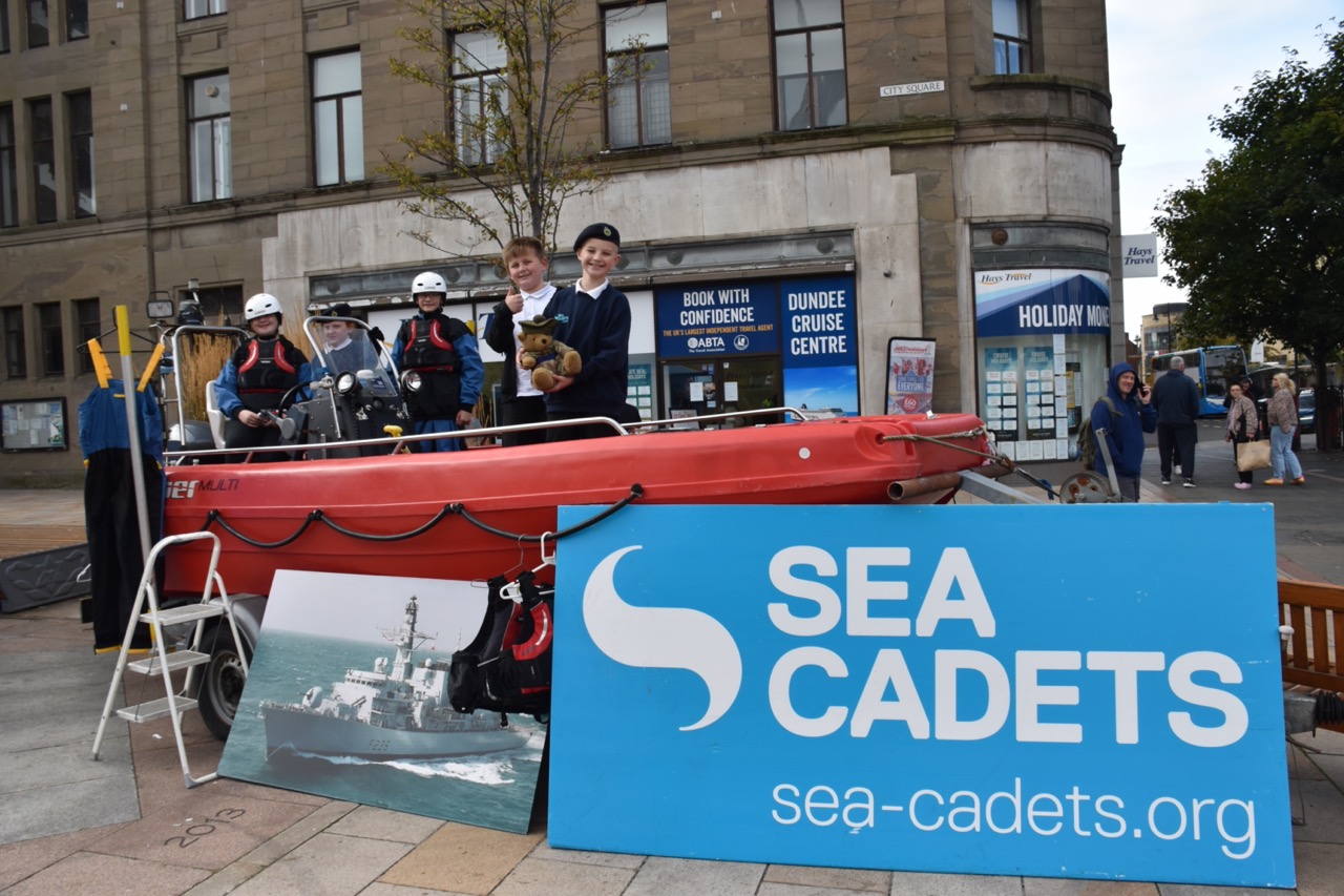 Children and a stuffed teddy bear on a dinghy.