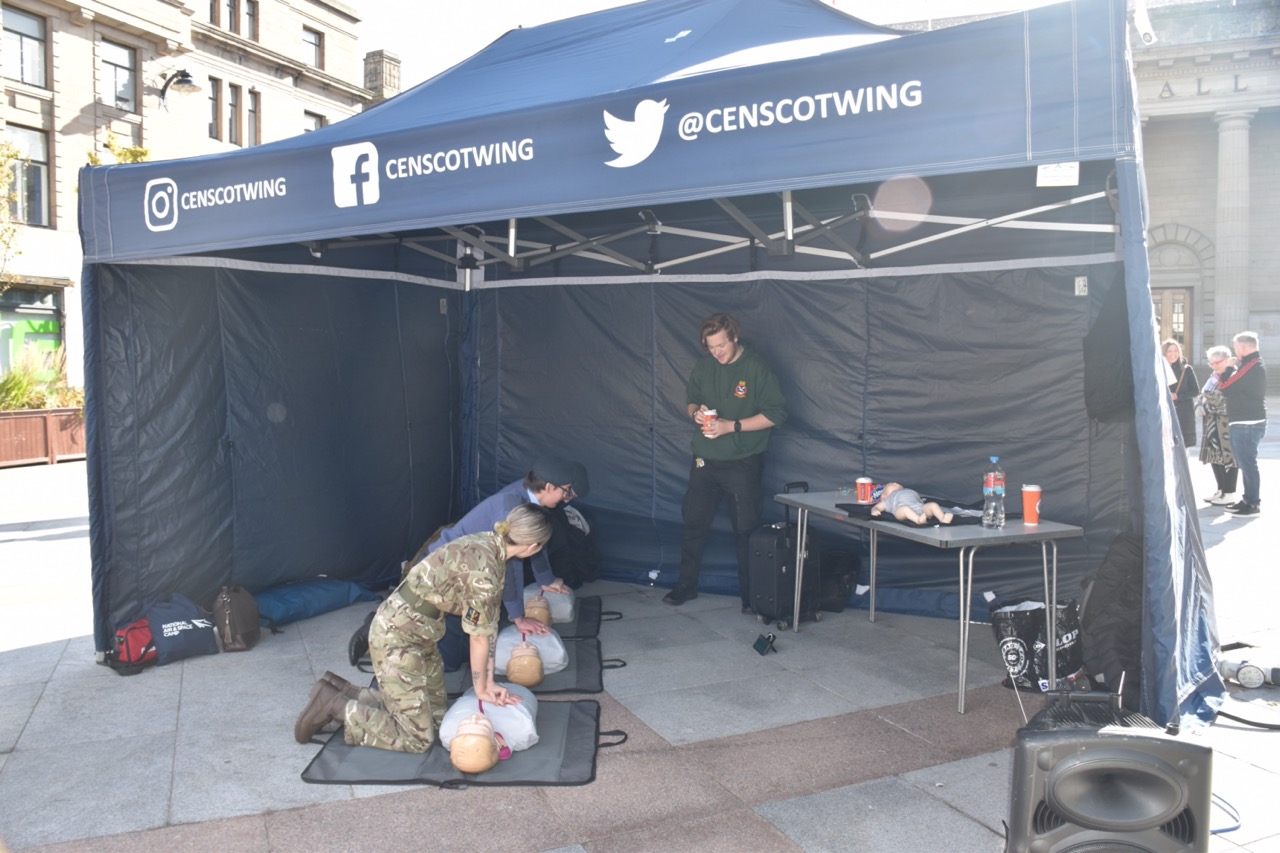 Three cadets performing chest compressions on training dummies.