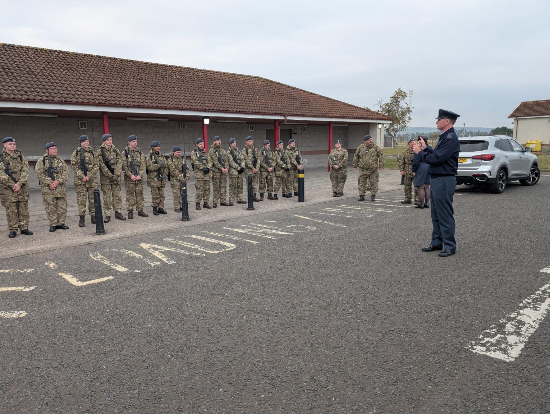 Cadets holding rifles receive instructions from an Adult Volunteer.