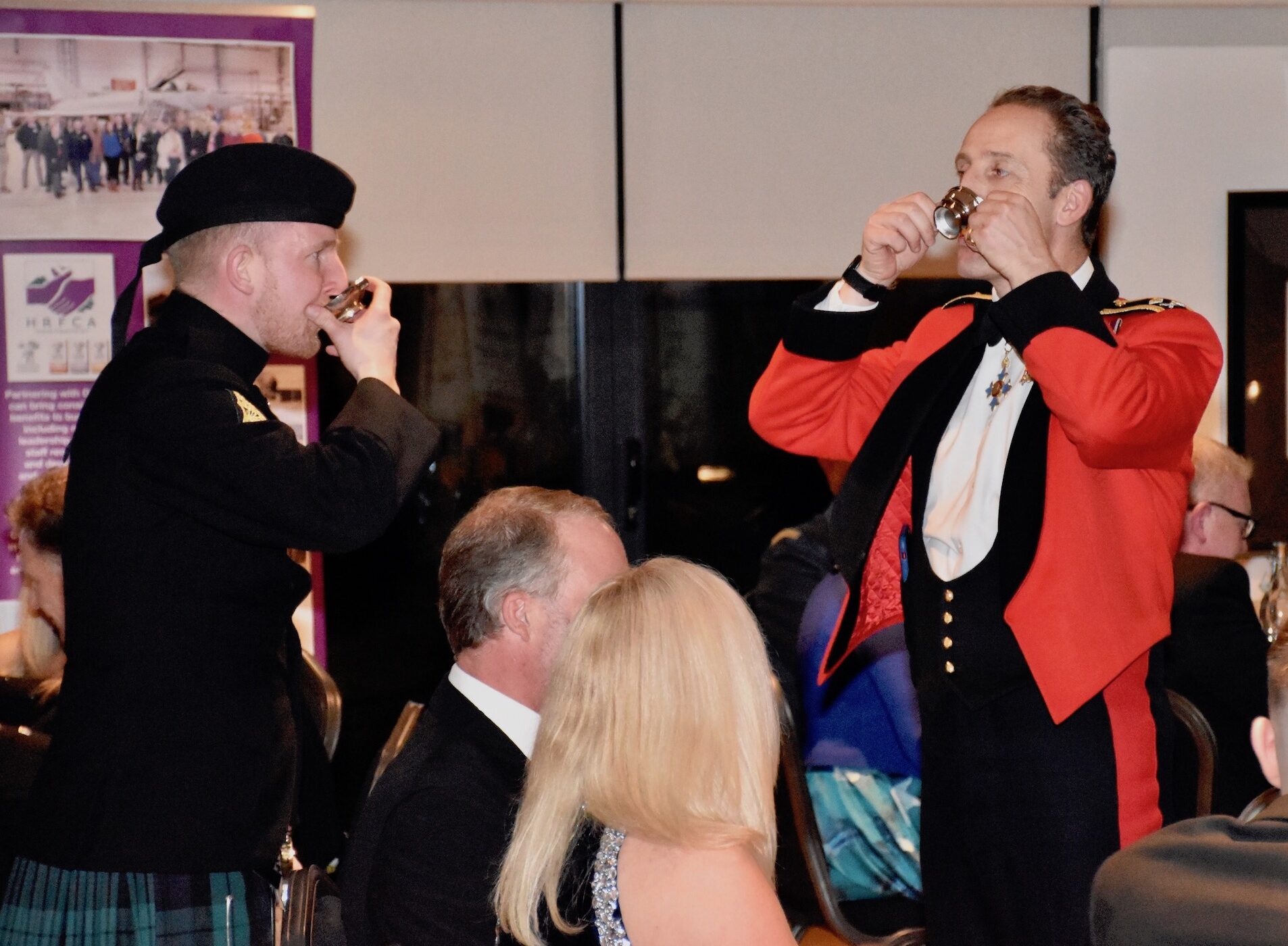 General Lindsay and Private Murray lift quaichs, toasting the King.
