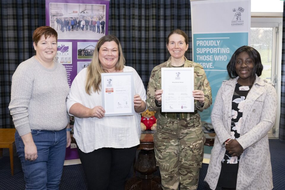Three representatives from Moray Business Women with Group Captain Brewin at RAF Lossiemouth. They are displaying the Armed Forces Covenant and Employer Recognition Scheme Bronze Award.