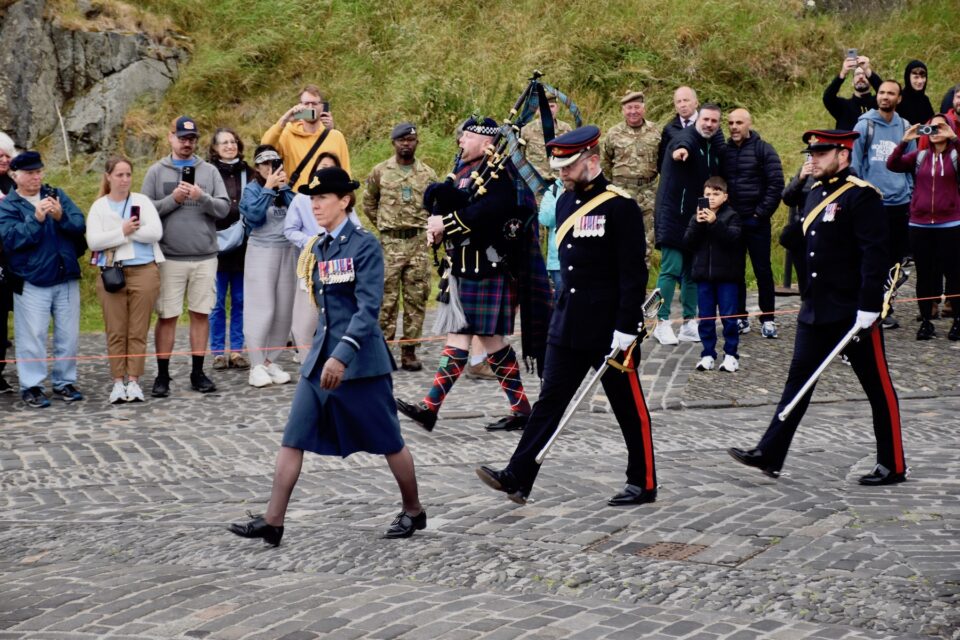 Air Commodore Phythian moves to the dais accompanied by 105th Regiment Royal Artillery and a piper from the Scotland and North Irish Yeomanry at Edinburgh Castle.
