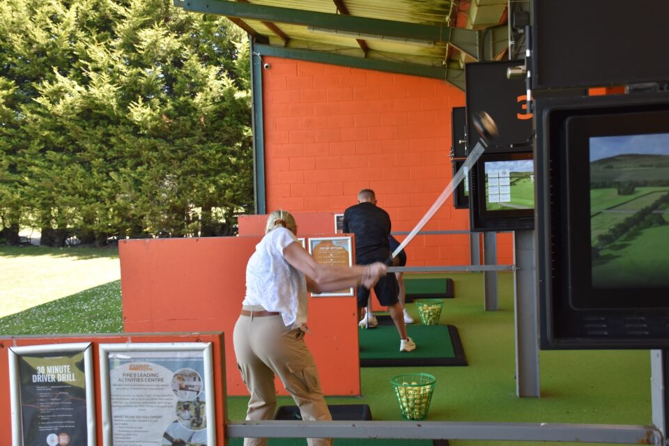 Several people hitting golf balls at the Cluny Activities driving range.